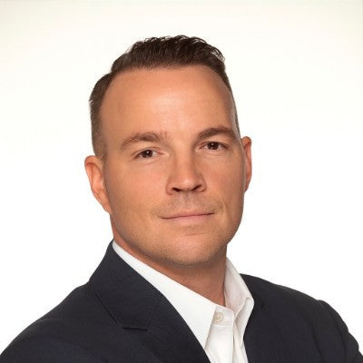 Man wearing a dark suit and white shirt against a plain background