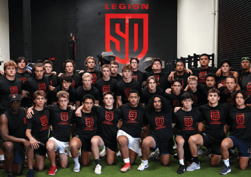 Group of people posing for a photo in front of a 'Legion' logo.